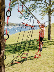 Child playing on a tree swing set with a scenic background of water and trees.