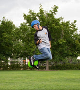 Person performing a trick on a scooter in a park with trees and grass in the background