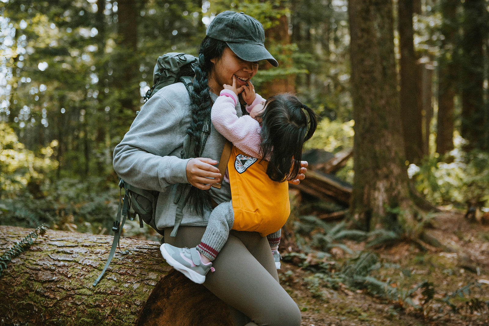 Woman and child hugging on a log in a forest